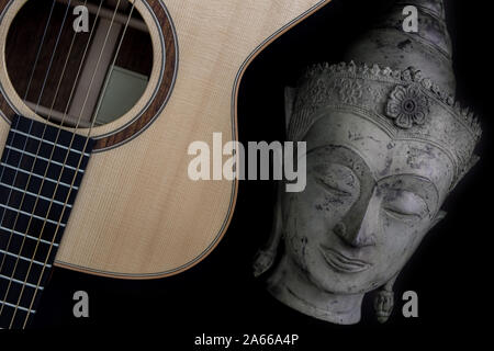 Musica spirituale. Meditando tradizionale statua del Buddha con acustica chitarra folk. Che rappresenta la terapia di musica, musica religiosa e guarire la mente. Chi Foto Stock