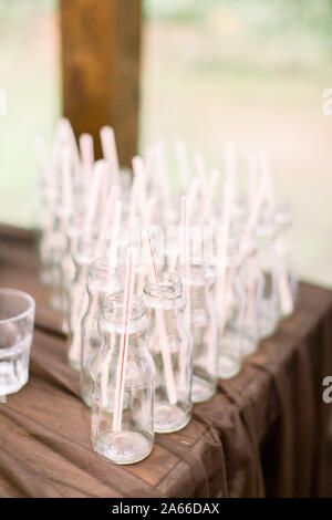 Bottiglie per la limonata sul tavolo in legno all'esterno. Set di bottiglie in vetro per la limonata e cocktail. Catering, ricevimento di nozze concetto. Foto Stock