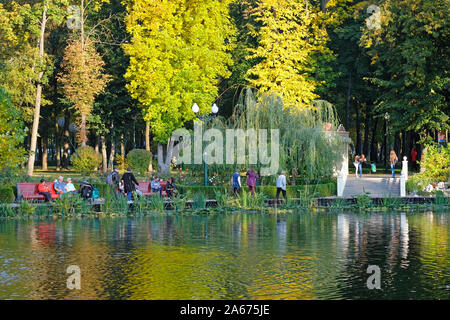 In un parco della città sulle rive del laghetto, le persone a rilassarsi. Gli alberi sono coperti con il giallo e il verde delle foglie, l'autunno è venuta. Trascorrere il tempo libero in Foto Stock