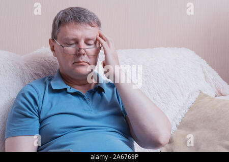 Mal di testa in una stanca uomo di mezza età con gli occhiali Foto Stock