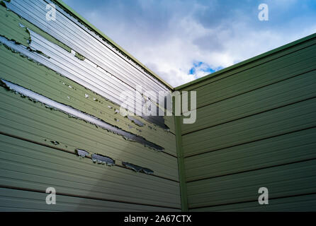 Guardando il verde usurato e pareti scrostate uscendo di alluminio unità di storage Foto Stock