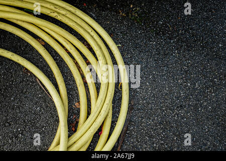 Giallo tubo flessibile avvolto e giacente a terra. Foto Stock