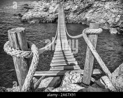 Appendere il ponte di legno collegare rocciosa costa del mare Foto Stock