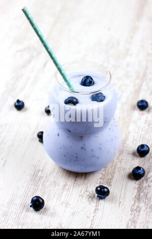 Frullato di mirtilli in vetro con una cannuccia. Bevande dietetiche fatta con mirtilli freschi e yogurt Foto Stock