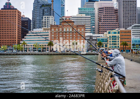 San Francisco, Stati Uniti d'America - 14 Maggio 2018: Fisher su Pier 14 con la città di grattacieli in rassegna Foto Stock