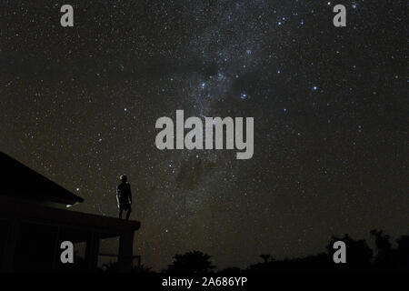 Da sola la donna sul tetto guardando mliky modo e le stelle nel cielo notturno sull isola di Bali Foto Stock