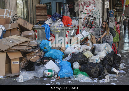 Una donna di discariche di rifiuti a parte la strada a Patrasso.comune i lavoratori di tutta la Grecia hanno lanciato una 48 ore di sciopero per protestare contro i piani del governo a portata di mano oltre ad investitori privati della parte comune dei servizi. Lo sciopero mostra già il suo primo impatto con sacchetti di rifiuti ammucchiati sulle strade. Foto Stock