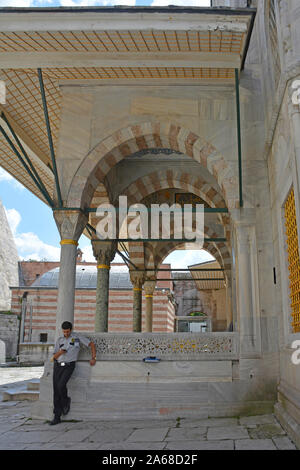 Istanbul, Turchia - 5 settembre 2019. Una guardia di sicurezza controlla il suo telefono portico esterno del XVI secolo la tomba del Sultano Selim II nella tomba di S Foto Stock