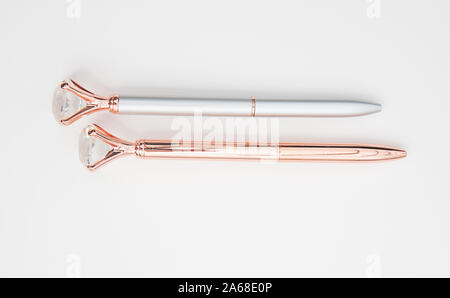 Due fancy scrivono penne rose gold e silver e isolate su uno sfondo luminoso. Entrambi hanno un diamante faux gioiello alla fine delle penne. Forniture per uffici Foto Stock