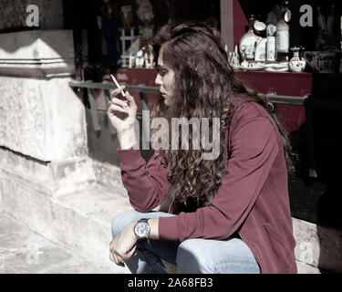 Montenegro, Sep 21, 2019: giovane donna seduta e Sigaretta fumare al di fuori di un negozio di antiquariato in Kotor Old Town Foto Stock