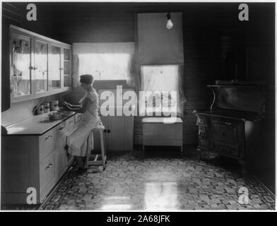 Donna sbucciare le patate in una moderna azienda agricola cucina Foto Stock