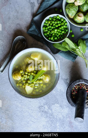 Pasto leggero, i cavoletti di Bruxelles e la zuppa di piselli con patate in una piastra di ceramica Foto Stock