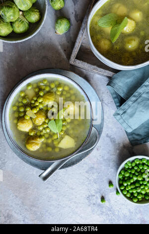 Pasto leggero, i cavoletti di Bruxelles e la zuppa di piselli con patate in una piastra di ceramica Foto Stock