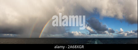 Spettacolare vista panoramica di una cloudscape durante una piovosa e colorata mattina con un brillante arcobaleno doppio. Presa sull'oceano Pacifico in Alaska, Stati Uniti d'America. Foto Stock