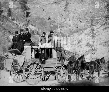 Vista laterale di un stagecoach; formalmente vestiti uomini in seduta e sulla parte superiore del pullman. Foto Stock