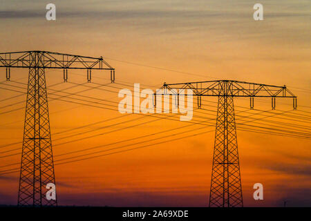 Linea di alimentazione ad alta tensione nella linea di trasmissione Sunset Pylons Germany ENERGY Foto Stock