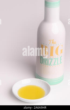 Olio di oliva versata in un piccolo piatto bianco isolato su sfondo bianco Foto Stock