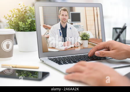 Medico con uno stetoscopio sul computer allo schermo del laptop. La telemedicina o la telesanità concetto. Foto Stock
