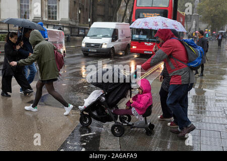 Una famiglia visitando la capitale di resistere a pioggia pesante in un pomeriggio autunnale in Trafalgar Square, il 24 ottobre 2019, in Westminster, Londra, Inghilterra. Foto Stock