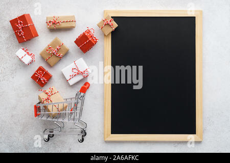 Confezioni regalo volare al di fuori di un carrello e vuoto lavagna con copia spazio. Vendita stagionali e modello di sconto. Foto Stock