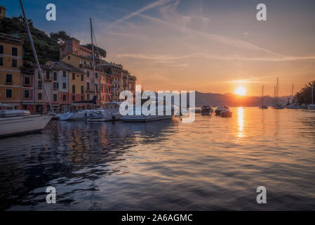 Sunrise sulla Riviera Italiana a Portofino con barche ormeggiate nel porto tranquillo e colorati edifici waterfront visualizzati sopra l'acqua Foto Stock