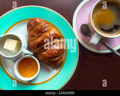 La prima colazione continentale con croissant, marmellata di frutta, burro, caffè, color menta e piastre di rosa Foto Stock