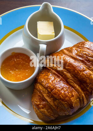 Dolce burroso croissant, fruttato marmellata, burro ricciolo sulla piastra blu Foto Stock