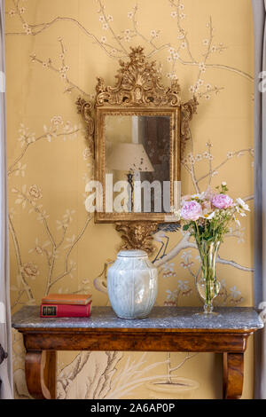 Scrofetta decorativi specchio incorniciato sopra la console in marmo con de Gournay wallpaper Foto Stock