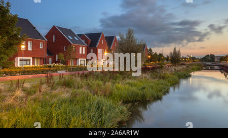 Esposizione lunga notte immagine della strada suburbana con ecologici moderni case famiglia con eco friendly banca di fiume in Veenendaal città, Paesi Bassi. Foto Stock