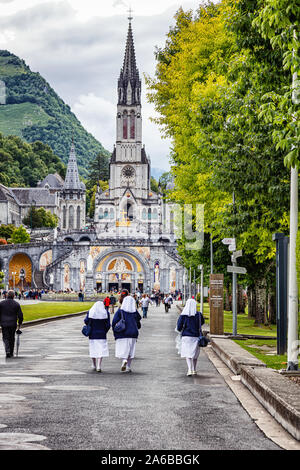 LOURDES - Giugno 15, 2019: vista delle monache sul fondo di Notre Dame du Rosaire basilica a Lourdes, Francia Foto Stock