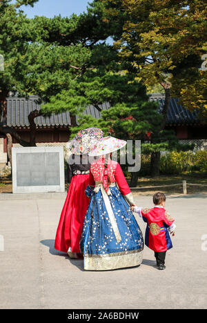 Due giovani ragazze con un piccolo ragazzo in nazionale coreano costumi passeggiando lungo Chandeokgung Palace, Seoul, Corea del Sud Foto Stock