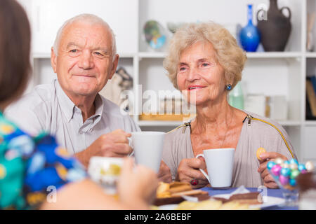 Ritratto di felice coppia matura con femmina valutazione bere il tè in cucina Foto Stock