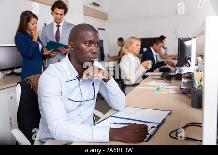 Ritratto di concentrato giovane imprenditrice afro-americano a pensare a un nuovo progetto di business nella moderna coworking space Foto Stock