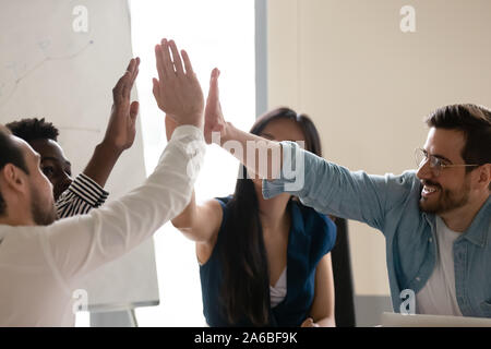 Diversi dipendenti dando alta cinque alla riunione, celebrando il successo Foto Stock