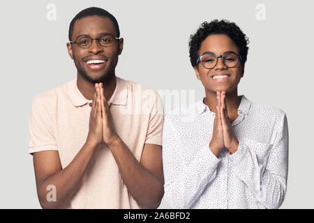 Colpo alla testa sorridente americano africano giovane tenendo le mani in preghiera Foto Stock