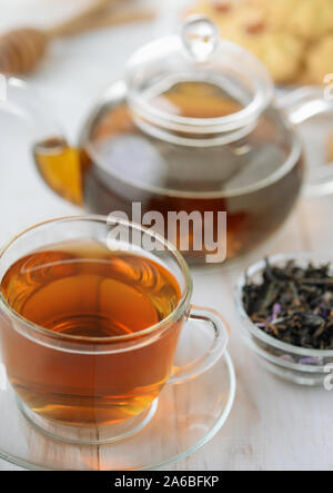 Teiera in vetro e la tazza di tè alle erbe su bianco tavolo in legno Foto Stock