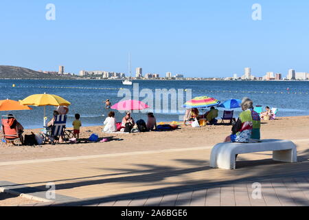 Vacanzieri seduti sulla spiaggia a Mar de Cristal, Mar Menor, Murcia, Spagna Foto Stock