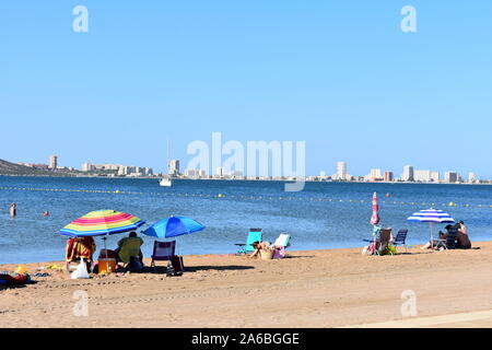 Vacanzieri seduti sulla spiaggia a Mar de Cristal, Mar Menor, Murcia, Spagna Foto Stock