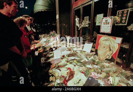Fiori e persone in lutto al di fuori i grandi magazzini Harrods, guardando le foto della principessa Diana e Dodi Fayed, nei giorni seguenti il funerale della principessa Diana, a Londra, Inghilterra, settembre 1997. Foto Stock