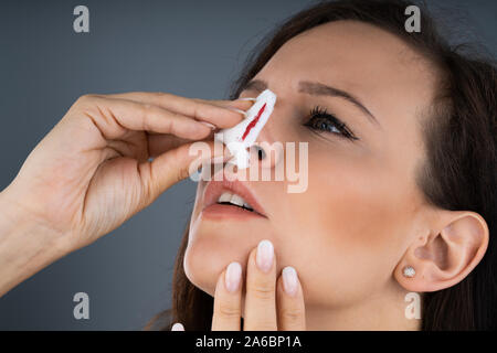 Donna cerca di fermare il sangue che fuoriesce dal naso Foto Stock