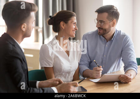 Felice giovane coppia sorridente a discutere i dettagli del contratto Foto Stock