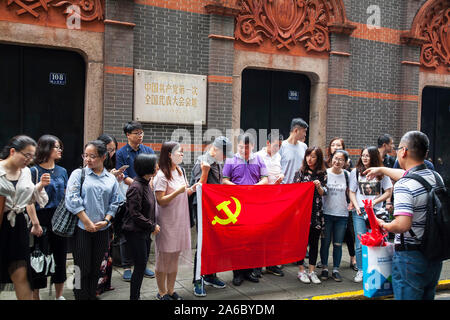 Lavoratori con bandiera cinese al di fuori del sito del primo Congresso nazionale del Partito Comunista Cinese Xintiandi, sulla strada Xingye Foto Stock