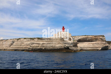 Cliffed costa e un faro rosso vicino alla città di Bonifacio in Corsica Francia visto dal mare Mediterraneo Foto Stock