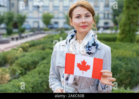 Donna adulta con il Canada bandiera su una città sullo sfondo. Foto Stock