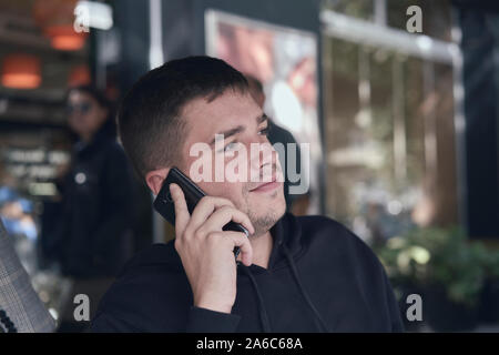 Giovane uomo chiamando con il suo telefono cellulare in un bar terrazza Foto Stock
