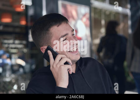Giovane uomo chiamando con il suo telefono cellulare in un bar terrazza Foto Stock