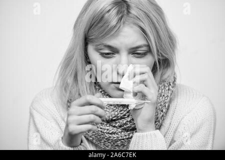 Prendere la temperatura e valutare i sintomi. Misurare la temperatura. La donna si sente male male starnuti. La ragazza di sciarpa tenere il termometro e il tessuto vicino. Freddo e rimedi influenza. Alta temperatura del concetto. Foto Stock