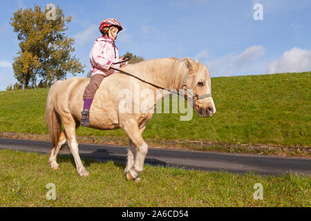 Una bambina a cavallo di un pony. Foto Stock