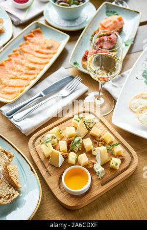 Il piatto di formaggi. Focus sulla deliziosa miscela di formaggio con le noci, miele sul tavolo di legno. Vari snack e antipasti in tavola. Il menu del ristorante. Foto Stock