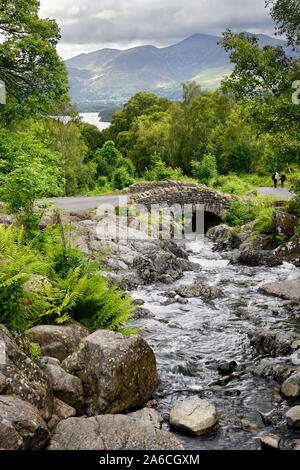 Giovane sulla strada a Ashness ponte Barrow Beck che fluisce al lago Derwentwater e Keswick sotto Skiddaw Mountain Lake District Inghilterra Foto Stock